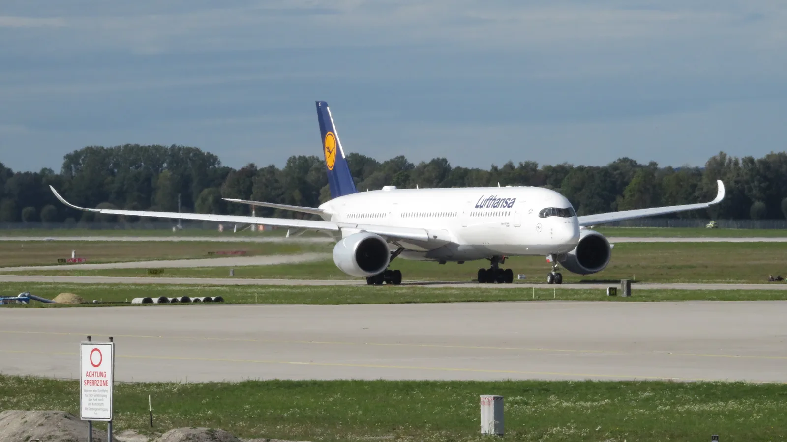 A Lufthansa Airbus A350-900 taxiing at Munich Airport in evening light, crane logo on the tail fin