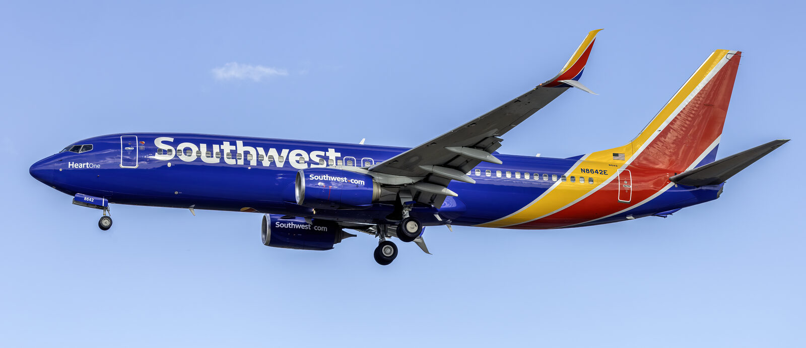 Southwest Airlines Boeing 737-800 in blue, red and yellow Heart livery on final approach against a clear blue sky