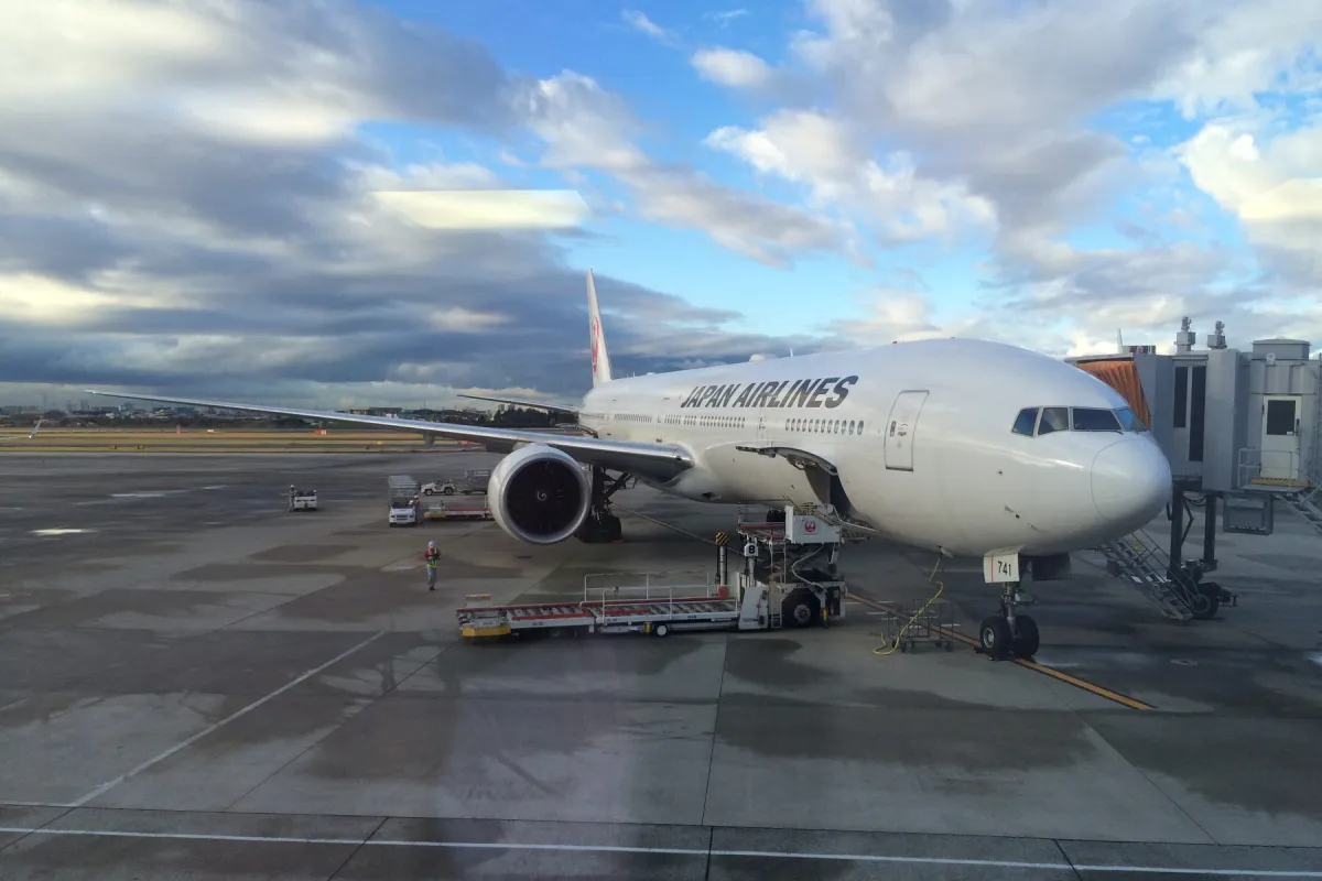 A passenger jet on the airport apron under a blue sky with scattered cloud.